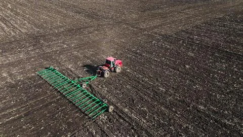 The red tractor works in the field in the spring Stock Photos