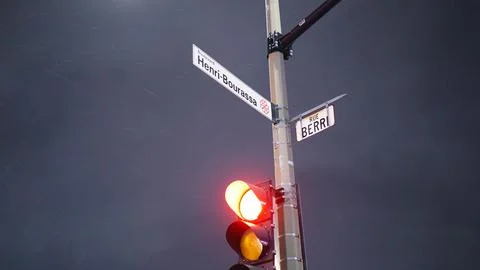 A red traffic light on a composite material pole with a street sign above it - Foto stock