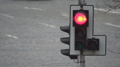 Red traffic light lights up against a background of moving cars on a city road Stock Footage 81716897