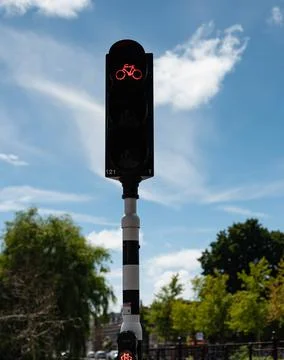 Red traffic light on a striped pole against a partly cloudy blue sky Fotos Stock