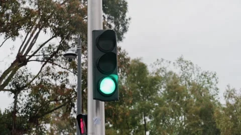 A red traffic light turning green in a city intersection with a pedestrian .. Stock Footage 339440739