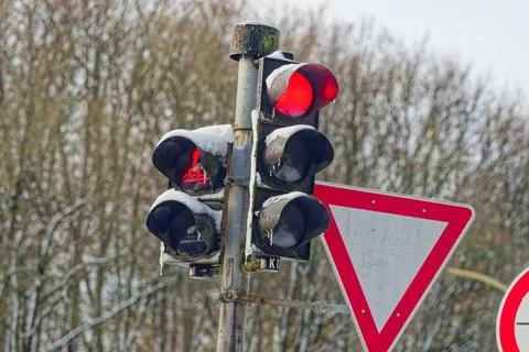Red traffic lights and yield sign covered with snow in winter outdoor setting Stock Photos