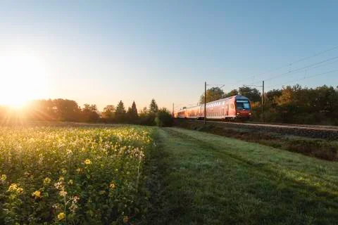 Red train and spring landscape at sunrise. Spring travel context Stock Photos