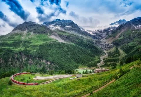 Red train Bernina Express to the passage in the mountains. Stock Photos