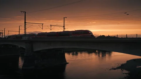 Red train crossing a bridge at golden sunset Stock Footage 314993366