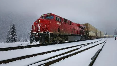 Red train engine pulling cargo in the snow Stock Photos