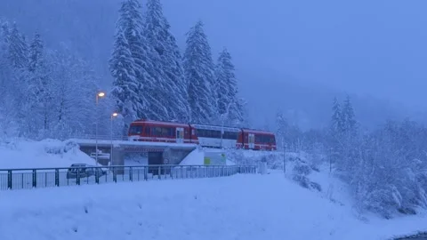 Red Train Going Along In The Snowy Alps Mountains at Dusk Stock Footage 235850548