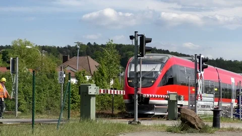 Red train passing by railroad crossing with gates, barriers opening Video stock 89305913