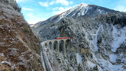 Red train passing through famous mountain in Filisur, Switzerland. Vídeos de archivo 240523762