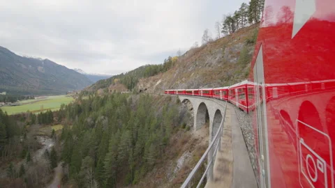 Red train passing through Landwasser Viaduct in Switzerland. Shot from window.  Stock Footage 253606094