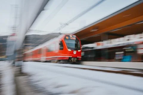 Red train speeding through snowy railway station platform Stock Photos