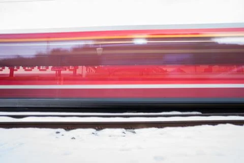 Red train speeding on tracks in winter snow Stock Photos