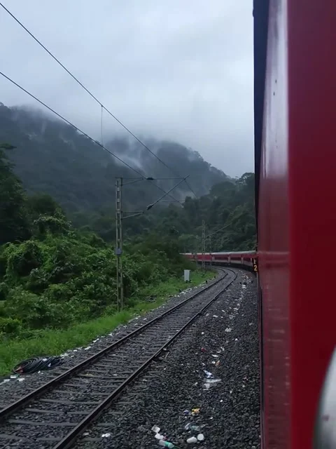 Red Train Traveling on Mountain Railway Track in Monsoon Video stock 342265090