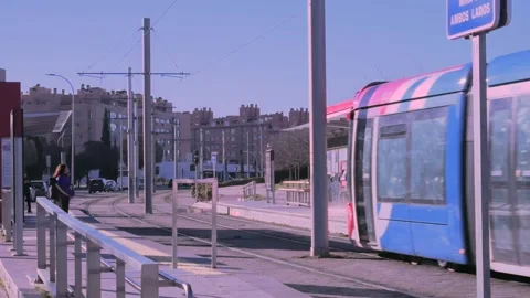 Red tram approaching station with waiting commuters in Sanchinarro, Madrid Stock Footage 301098903
