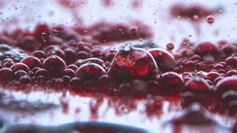 Red translucent bubbles lie on a soft mirrored surface going slow motion Stock Footage 132177193