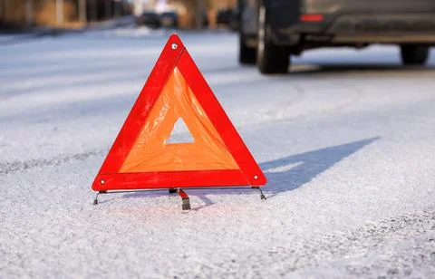 The red triangle of an emergency stop on a winter road at the place of a car Stock Photos