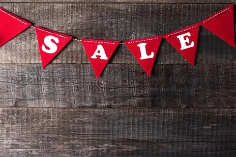 Red triangle flags hanging over wooden background with sign SALE Stock Photos