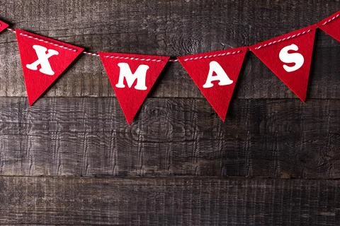 Red triangle flags hanging over wooden background with sign XMAS Stock Photos