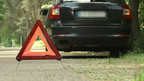 Red triangle, red emergency stop sign and black car with turned on blinkers Stock Footage 244195192