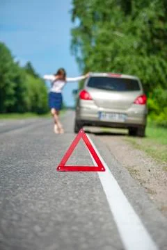 Red triangle warning sign and broken car on road Stock Photos