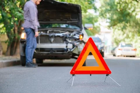 Red triangle warning sign of car accident on road. Triangle in front of wrecked Stock Photos