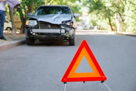 Red triangle warning sign of car accident on road. Triangle in front of wrecked Stock Photos