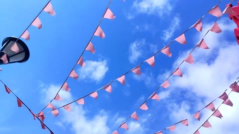 Red triangular flags flutter in the wind against a bright blue sky Stock Footage 306636548