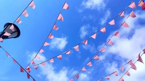Red triangular flags flutter in the wind against a bright blue sky Stock Photos
