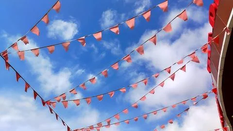 Red triangular flags flutter in the wind against a bright blue sky 写真素材
