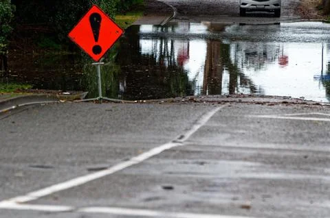 A red, triangular flood water sign with a black exclamation mark warn of fl.. Stock Photos