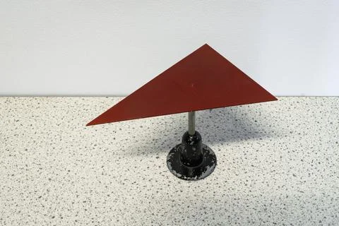 Red triangular metal plate is balancing on a needle 스톡 사진