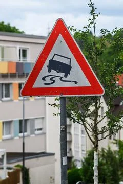 Red triangular slippery road warning sign mounted on a grey pole 写真素材