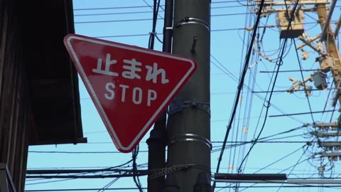 Red triangular stop warning traffic road sign with letters kanji standing street Stock Footage 170094808