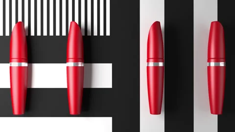 Red tubes of mascara roll on a black and white striped animated background. Stock Footage 141708798