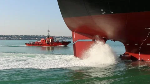 A Red Tugboat Assisting a Large Cargo Ship In The Waters Of A Port Stock Footage 266415723