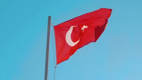 A red Turkish flag fluttering in the wind against a blue sky Stock Footage 323855114