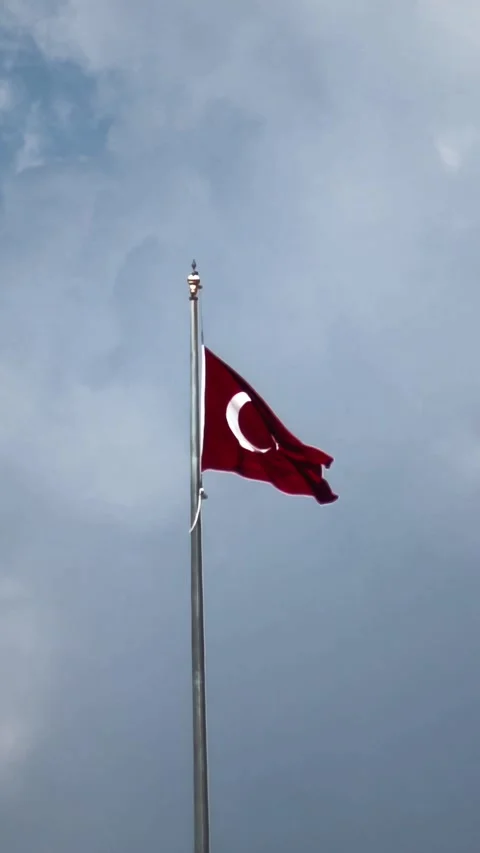 Red Turkish flag flutters in slow motion on tall flagpole against dramatic 스톡 동영상 330519146