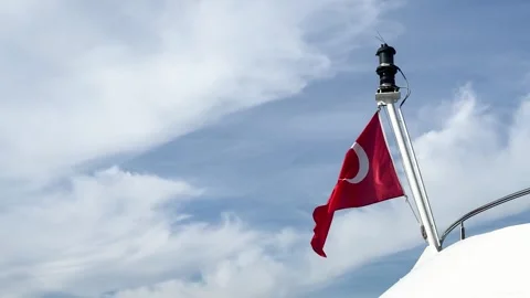A red Turkish flag flutters in the wind against a clear blue sky 스톡 동영상 321341486