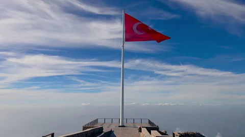 Red Turkish flag on mountain summit viewpoint above clouds - outdoor Stock Footage 346535663