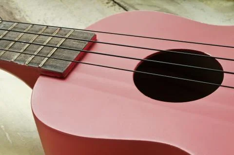 Red ukulele on wooden table Photos