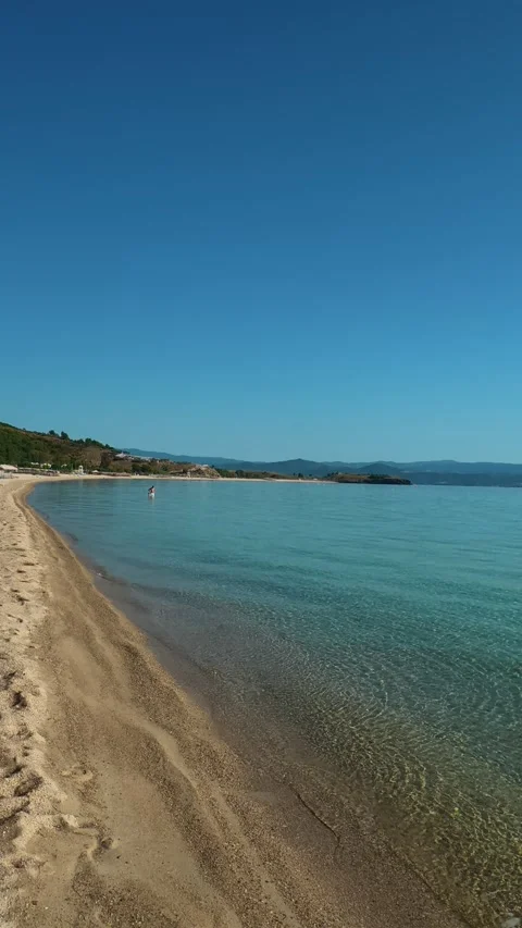 Red umbrellas line the shore. Trani Ammouda, Greece. Vertical Stock Footage 339629029