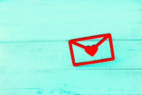 Red valentine card, in the form of a letter with a heart on a wooden blue bac Stock Photos