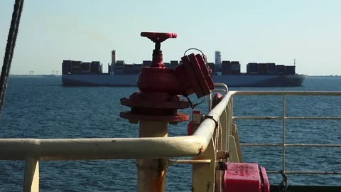 Red valve above thin yellow pipes against long merchant ship Stock Footage 113093641