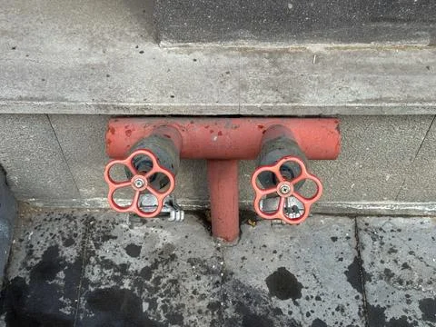 Red valve handles from a fire hydrant built into a residential building Stock Photos