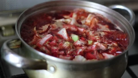 Red vegetable soup with beets cooked in a pan on the stove Stock Footage 130575837