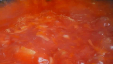 Red vegetable soup or tomato soup is cooked in pan and boil close up view Stock Footage 99023262