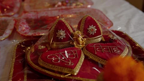 Red velvet wedding tilak boxes with gold script and small golden Ganesh idol Video stock 342396189
