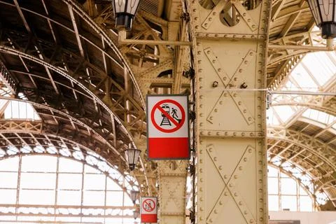 Red vertical Warning sign Do not leap from platform. Interior of railway station Stock Photos