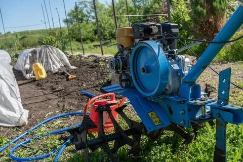 Red walk-behind tractor or tiller parked on grass in a rural garden. Agricu.. Stock Photos