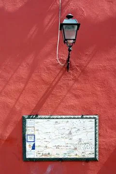 Red wall with ceramic map of Campagnano di Roma and street lamp 库存照片